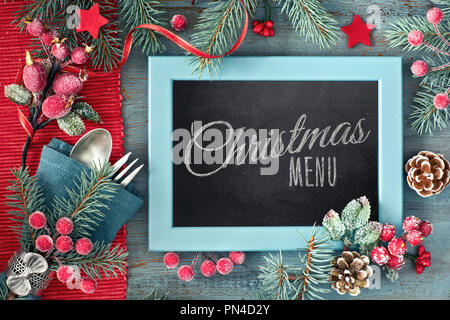 Dekoriert mit dunklem Hintergrund mit roten und grünen Dekorationen, Gabel und Löffel, Text "weihnachtsmenü" auf schwarz-Board Stockfoto