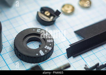 Teile sind vollständig demontiert alten retro Film SLR Kamera auf Millimeterpapier, close-up Stockfoto