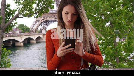 Junge Dame ziehen Smartphone, um Text vom Eiffelturm in Paris Antwort Stockfoto