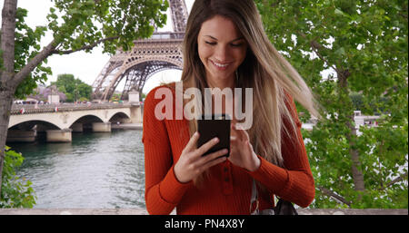 Junge Dame ziehen Smartphone, um Text vom Eiffelturm in Paris Antwort Stockfoto