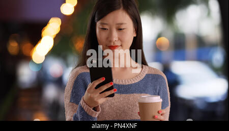 Nahaufnahme der glücklichen Frau liest Texte auf dem Smartphone vor der städtischen Cafe Stockfoto