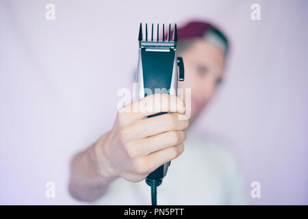 Junge männliche Hipster hält Rasierapparat isoliert Stockfoto