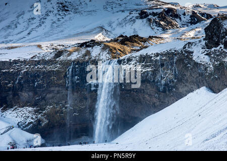 Touristen zum spektakulären Wasserfall Seljalandsfoss Seljalands im Süden Islands mit gletscherschmelze Gewässer aus Eyjafjahajokull Eiskappe Stockfoto