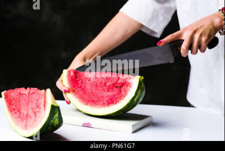 Frau, schneiden Wassermelone auf ein Schneidebrett Stockfoto