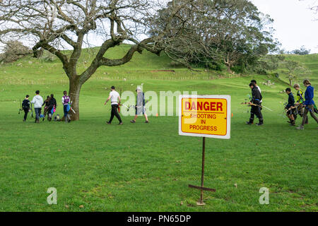 Warnschild Gefahr Schießen in Fortschritte bei der Gruppe von Bogenschützen zu Fuß zum Feld. Stockfoto