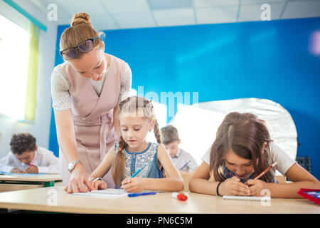 Lehrer Kind Hilfe bei den Hausaufgaben im Unterricht in der Schule Stockfoto