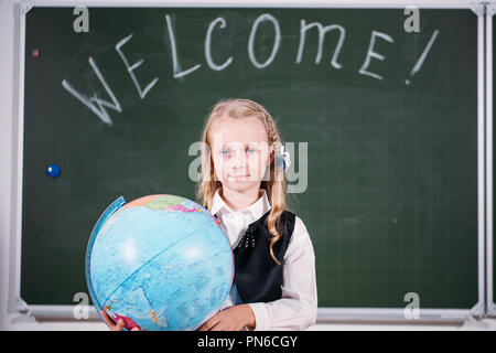 Schule Mädchen mit Globus im Klassenzimmer Tafel auf Hintergrund Stockfoto