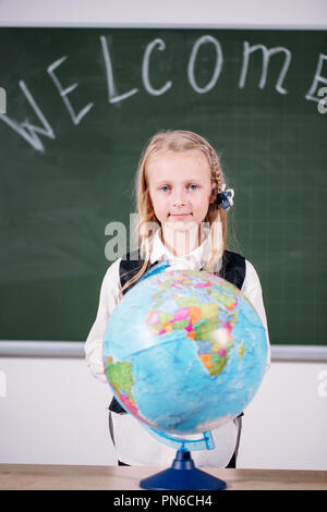 Schule Mädchen mit Globus im Klassenzimmer Tafel auf Hintergrund Stockfoto