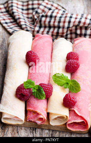 Gerollt Milch und Himbeer Pfannkuchen am Holztisch Stockfoto