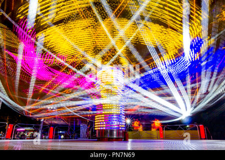 Lange Belichtung eines schnell drehenden bunten Karussell in der Nacht mit lebendigen Beleuchtungen beleuchtet, Kirmes Ride in Luna Park. Stockfoto