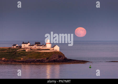 Roches Point, Irland. 28 Juni, 2018. Ein voller Mond erhebt als die letzten Sonnenstrahlen des Roches Point Leuchtturm im Hafen von Cork, Irland Leuchten Stockfoto