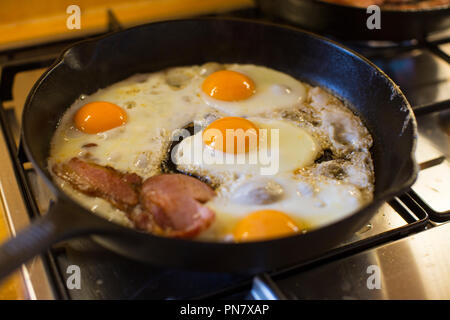 Spiegeleier und Speck Kochen in einer gusseisernen Pfanne. Stockfoto