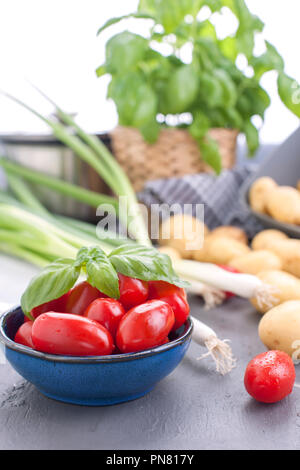 Junge Kartoffeln und Tomaten und frischen Zwiebeln. Zutaten für das Mittagessen Stockfoto