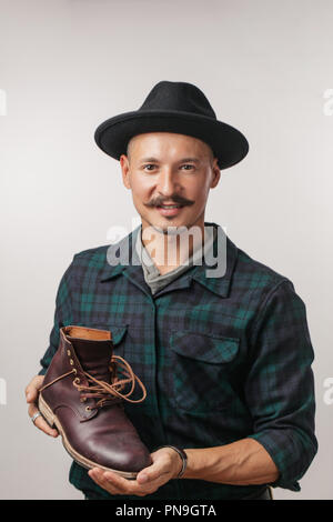 Foto der jungen fröhlichen Schuster Holding selbst gemacht Schuh über Weiß isoliert. Stockfoto