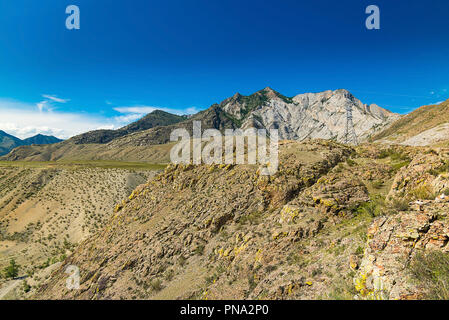 Die Oberfläche der Hügel und Berge, trockenen felsigen Boden, Berge in der Ferne, Stromleitungen in die wilden Berge Stockfoto