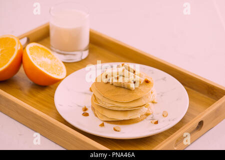 Stapel von leckeren Pfannkuchen mit Schokolade, Honig, Nüsse und Bananenscheiben auf Platte auf Stein Hintergrund Stockfoto