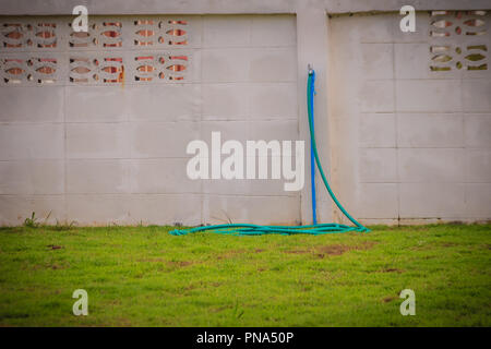 Grunge bronze Feld Wasserhahn mit blauem PVC-Rohr in weißen Wand Hintergrund verbunden. Stockfoto