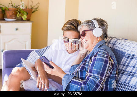 Paar junge und alte Großmutter und Teenager Neffe Familie Zeit zusammen Musik hören mit Kopfhörern und den Tag genießen. Glückliche Familie und Generationen Stockfoto