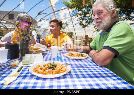 Großväter und Enkel zusammen in eine alternative biologische Natur Konzept Restaurant mit italienischer Pasta auf den Tisch Spaß in Radeln Stockfoto