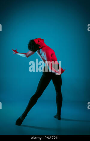 Die männlichen athletischen Ballet Dancer performing Tanz am strahlend blauen Hintergrund. Studio gedreht. Modernes Ballett, modernen Konzept. Fit jungen Mann. Kaukasische Modell Stockfoto