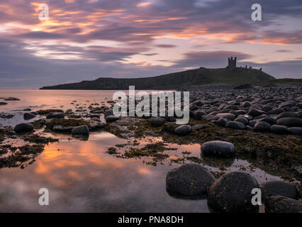 Dunstanburgh Castle bei Sonnenaufgang, Küste von Northumberland, England, Großbritannien Stockfoto