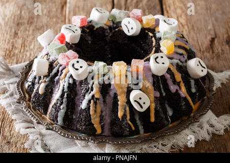 Schöne Bundt cake Reich mit kandierten Früchten, Eibisch und bunten Glasur close-up auf den Tisch dekoriert. Horizontale Stockfoto