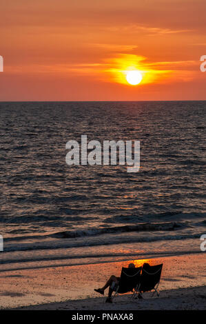 Eine Silhouette Paar in den Stühlen beobachten Sie den Sonnenuntergang entlang Bonita Beach in Bonita Springs, Florida. Stockfoto