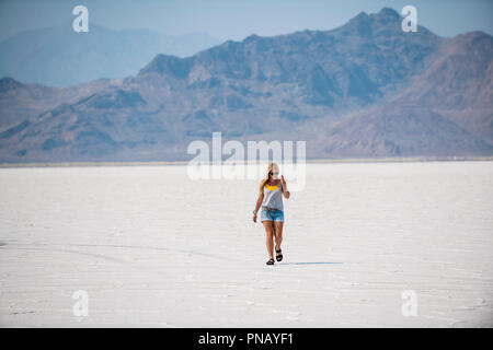 Eine blonde Frau geht über Bonneville Salt Flats, Tooele County, Utah, USA. Stockfoto