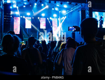 Masse, die mit erhobenen Händen vor der Bühne mit bunten Lichtern an der Music Festival. Stockfoto