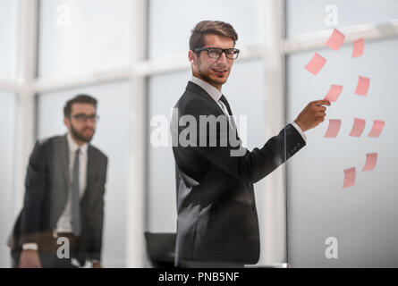 Mitarbeiter liest klebrig - Hinweise auf Glas. Stockfoto