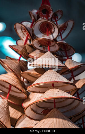 Orinetal, traditionelle Bambus und Stroh Hüte. Stapel von conic sun Hüte, rotem Futter und Blau, verschwommenen Hintergrund. Stockfoto