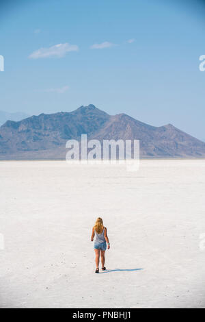 Eine blonde Frau geht über Bonneville Salt Flats, Tooele County, Utah, USA. Stockfoto