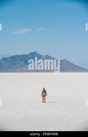 Eine blonde Frau geht über Bonneville Salt Flats, Tooele County, Utah, USA. Stockfoto