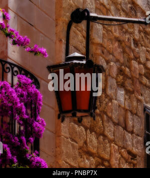 Eine alte Laterne hängend neben einem Balkon in einer typischen Straße in Mdina, Malta. Stockfoto