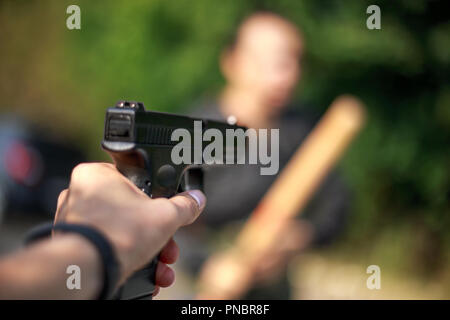 Person zeigen sie mit einem Gewehr auf die Angreifer. Fokus auf Gun. Die automatische Verteidigung Konzept. Stockfoto