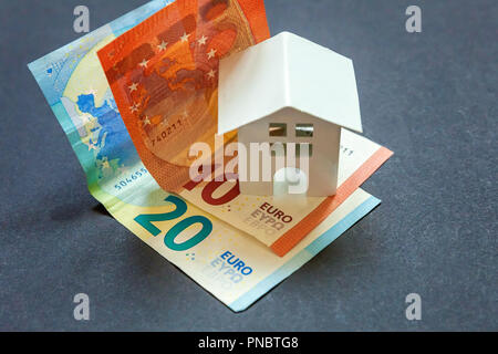 Euro-banknoten und symbolische kleines Spielzeug Haus. Kauf von Immobilien und Hypotheken Stockfoto