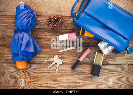 Blaue Geldbörse, Regenschirm und Zubehör. Dinge, die von den geöffneten Dame Handtasche. Ansicht von oben. Getönten Bild. Stockfoto