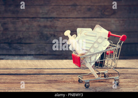 Warenkorb mit Pillen, die Spritze auf dem alten Holz Hintergrund. Getönten Bild. Stockfoto