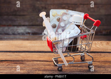 Warenkorb mit Pillen, die Spritze auf dem alten Holz Hintergrund. Getönten Bild. Stockfoto