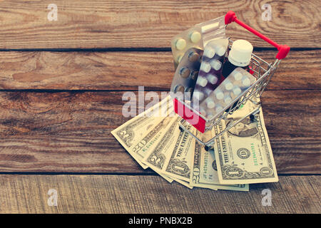 Warenkorb mit Pillen, eine Spritze, Kerzen, Dollar auf dem alten Holz Hintergrund. Getönten Bild. Stockfoto