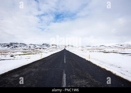 Die asphaltierte Straße Route von und nach Reykjavik obwohl Lavafelder im Süden Islands mit schneehöhe Markierungen am Straßenrand. Stockfoto
