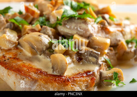 Gebratenes Schweinefleisch mit saurer Sahne Sauce, Pilze und grüne Petersilie - Nähe zu sehen. Stockfoto