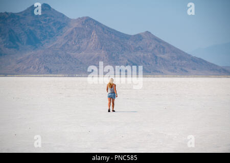 Eine blonde Frau geht über Bonneville Salt Flats, Tooele County, Utah, USA. Stockfoto