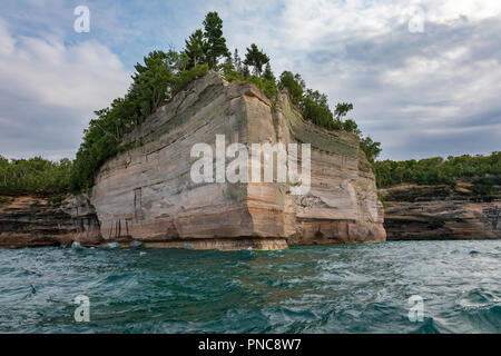 Eine felsige Stelle, mit Bäumen bedeckt, zeigt die Felswand auf die dargestellten Felsen National Lakeshore in Munising Michigan. Der Punkt ist von der w umgeben Stockfoto