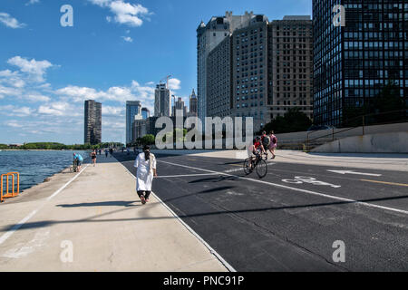 Fahrradfahrer und Fußgänger, direkt am Wanderweg auf dem Lake Shore Drive mit Blick auf die Skyline von Chicago, IL. Stockfoto