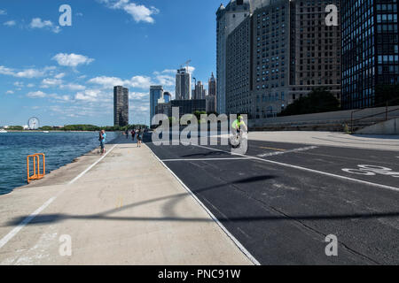 Fahrradfahrer und Fußgänger, direkt am Wanderweg auf dem Lake Shore Drive mit Blick auf die Skyline von Chicago, IL. Stockfoto