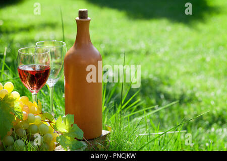Rose Wein Flaschen, Gläser und Trauben. Outdoor im Weinberg mit Platz für Ihren Text Stockfoto