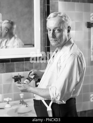 1920er Jahre älteren Mann, der Ärmel AM WASCHBECKEN AUF KAMERA QUETSCHEN PFLEGE PRODUKT AUS ROHR IN DER HAND - b10305 HAR 001 HARS Ausdrücke im mittleren Alter B&W Mann mittleren Alters AUGENKONTAKT PFLEGEN VOR STARREN OLDSTERS ALTEM KRAFT WAHL WISSEN STOLZ, SICH IN DEN ÄLTESTEN ÄRMEL VERBINDUNG STARE STILVOLLE graues Haar intensive DURCHDRINGENDE QUETSCHEN SCHWARZ UND WEISS KAUKASISCHEN ETHNIE HAR 001 NEUTRAL ALTMODISCHE FRAGENDE Stockfoto