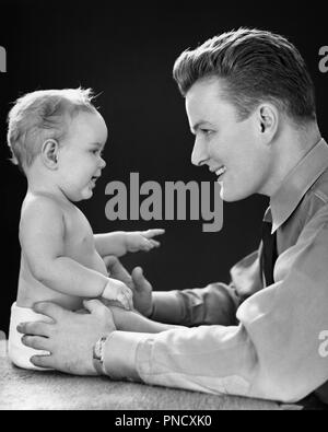 1940 s lächelnden jungen MANN VON ANGESICHT ZU ANGESICHT AUGE IN AUGE MIT BLICK AUF JAHRE ALTEN MÄDCHEN TOCHTER SITZEN BIS-b 1168 HAR 001 HARS LIFESTYLE FEIER FRAUEN STARTSEITE LEBEN MIT HALBER LÄNGE TÖCHTER PERSONEN INSPIRATION PFLEGE SPIRITUALITÄT VERTRAUEN VÄTER B&W GLÜCK KOPF UND SCHULTERN FRÖHLICHE KRAFT VATIS AUFREGUNG mächtig stolz LÄCHELN VON ANGESICHT ZU ANGESICHT VERBINDUNG AUGE IN AUGE FREUDIGE stilvolle Wachstum von Jungfischen ein Jahr alt das Miteinander junger erwachsener Mann BABY GIRL SCHWARZ UND WEISS KAUKASISCHEN ETHNIE HAR 001 ALTMODISCH, die da oben sitzen, Stockfoto