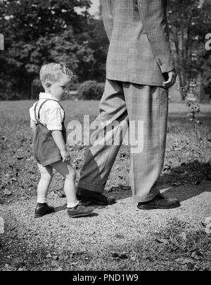 1940 JUNGE HINTER MANN IN seines Vaters Fußstapfen-j 10745 HAR 001 HARS KOPIE RAUM VOLLER LÄNGE PERSONEN INSPIRATION MÄNNER VÄTER B&W ERFOLG MENTOR SEINE STILE VATIS FÜHRUNG FORTSCHRITTE VATER UND SOHN RICHTUNG STOLZ RÜCKANSICHT FOLGENDE GENERATION VATER Verbindung des konzeptionellen Beispiel folgen Spuren führen LEGACY STILVOLLE BABY BOY RÜCKANSICHT MODEN Wachstum von Jungfischen Mitte - Mitte - erwachsene Menschen miteinander SCHWARZ UND WEISS HAR 001 ALTMODISCH Stockfoto